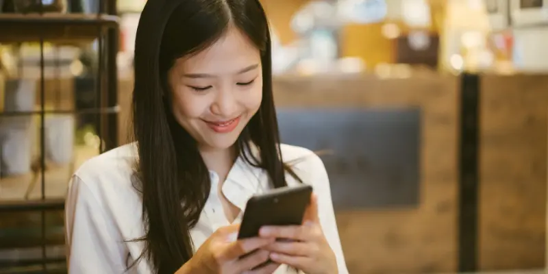 A Woman Is Chatting With Her Phone And Smiling